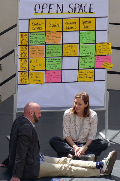 Nahaufnahme eines Whiteboards mit einem Zeitplan, der verschiedene Workshop-Titel und Uhrzeiten auflistet.