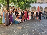 Gruppe von Menschen steht lächelnd auf gepflastertem Hof vor einem Gebäude.