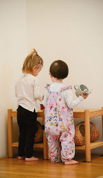 zwei spielende Kleinkinder stehen vor einem Tisch