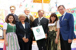 LR Christian Buchmann (rechts) mit der Familie Rüdiger bei der Überreichung des Landeswappens im Vergnügungspark der Grazer Messe.