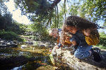 Symbolbild in Form von Kindern, die an einem Fluss sitzen und ihre Umgebung erforschen