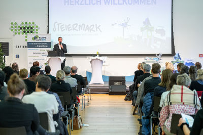 Moderator Oliver Zeisberger am Podium, Fotoaufnahme von hinten in die vollen Ränge 