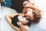 Ein Mann und eine Frau liegen mit am Boden, den Kopf zu einander gedreht und umarmen sich zärtlich. Ein Mann und eine Frau liegen mit am Boden, den Kopf zu einander gedreht und umarmen sich zärtlich.