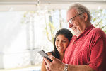 Symbolbild von einer älteren und einer jüngeren Person, die gemeinsam etwas am Smartphone ansehen. Symbolbild von einer älteren und einer jüngeren Person, die gemeinsam etwas am Smartphone ansehen.